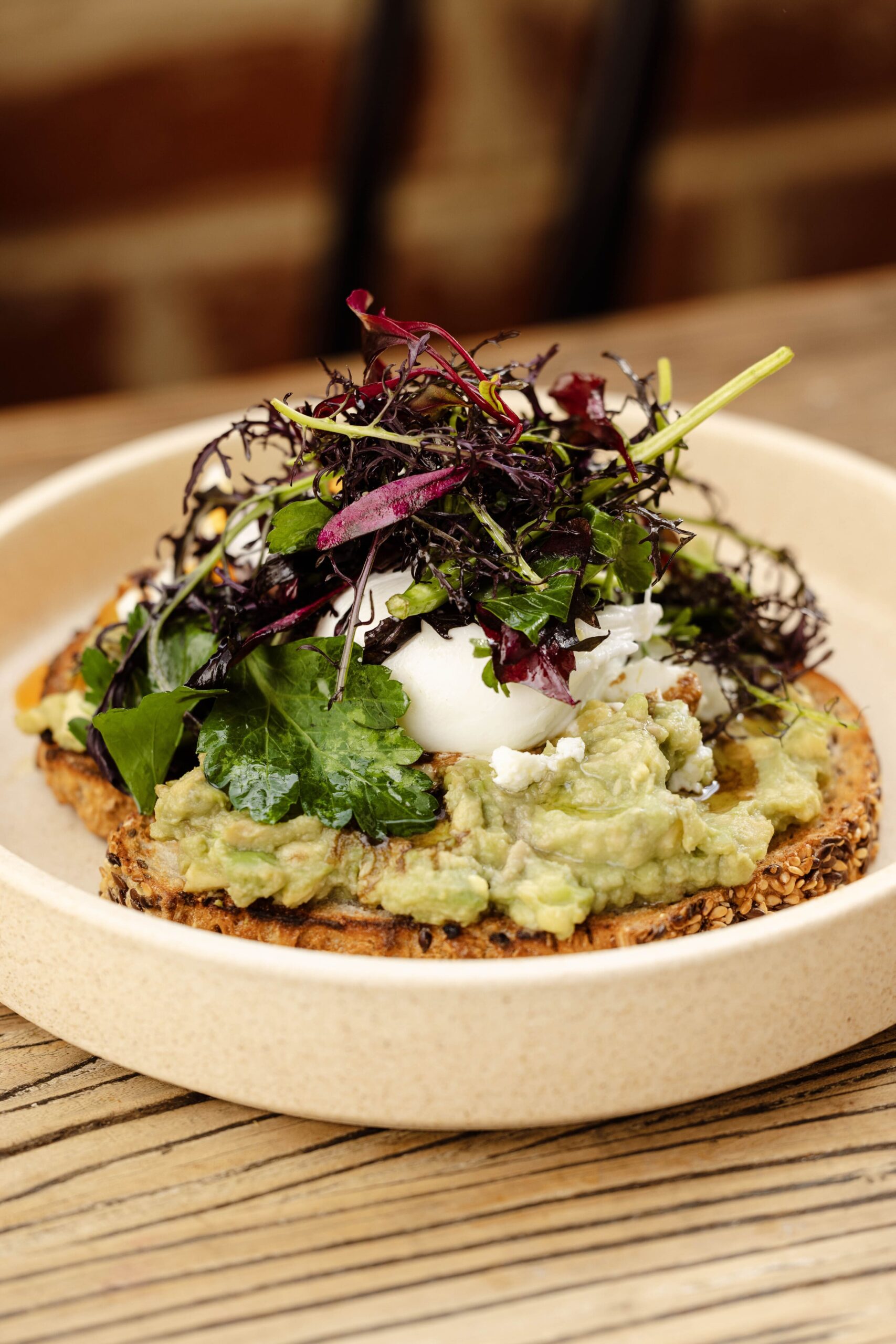 Avocado breakfast bruschetta topped with a poached egg, fresh herbs, and mixed greens, perfect for Mother's Day dining. A delicious, wholesome dish to enjoy on Mother's Day with family and friends.
