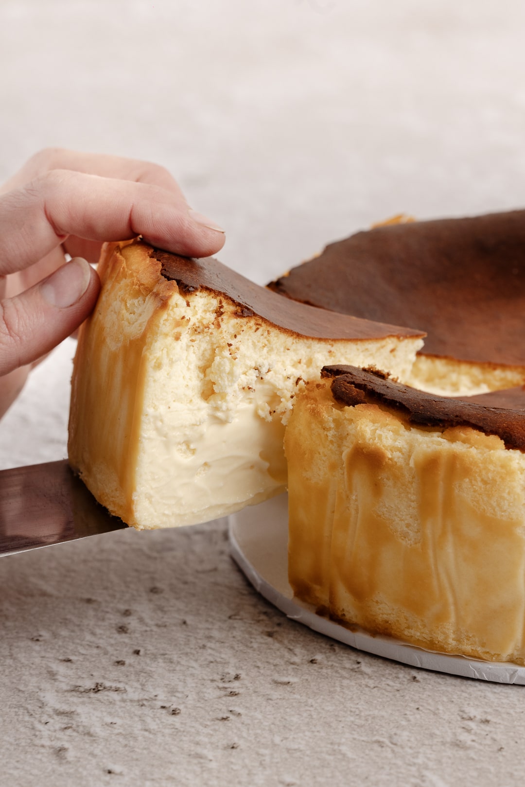 A slice of rich, creamy Basque cheesecake being served, with the top slightly browned, perfect for Mother’s Day dessert or as a sweet treat for any celebration.