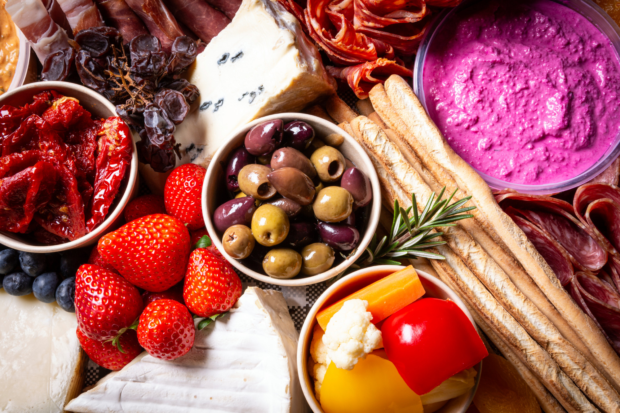 A colourful Mother's Day grazing platter featuring an assortment of cheeses, cured meats, fresh strawberries, olives, sun-dried tomatoes, colourful vegetables, and a dip, perfect for a Mother's Day picnic or family gathering.