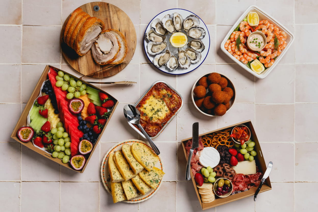 LaManna food spread on a table including porchetta roast garlic bread fruit platter prawns oysters and charcuterie