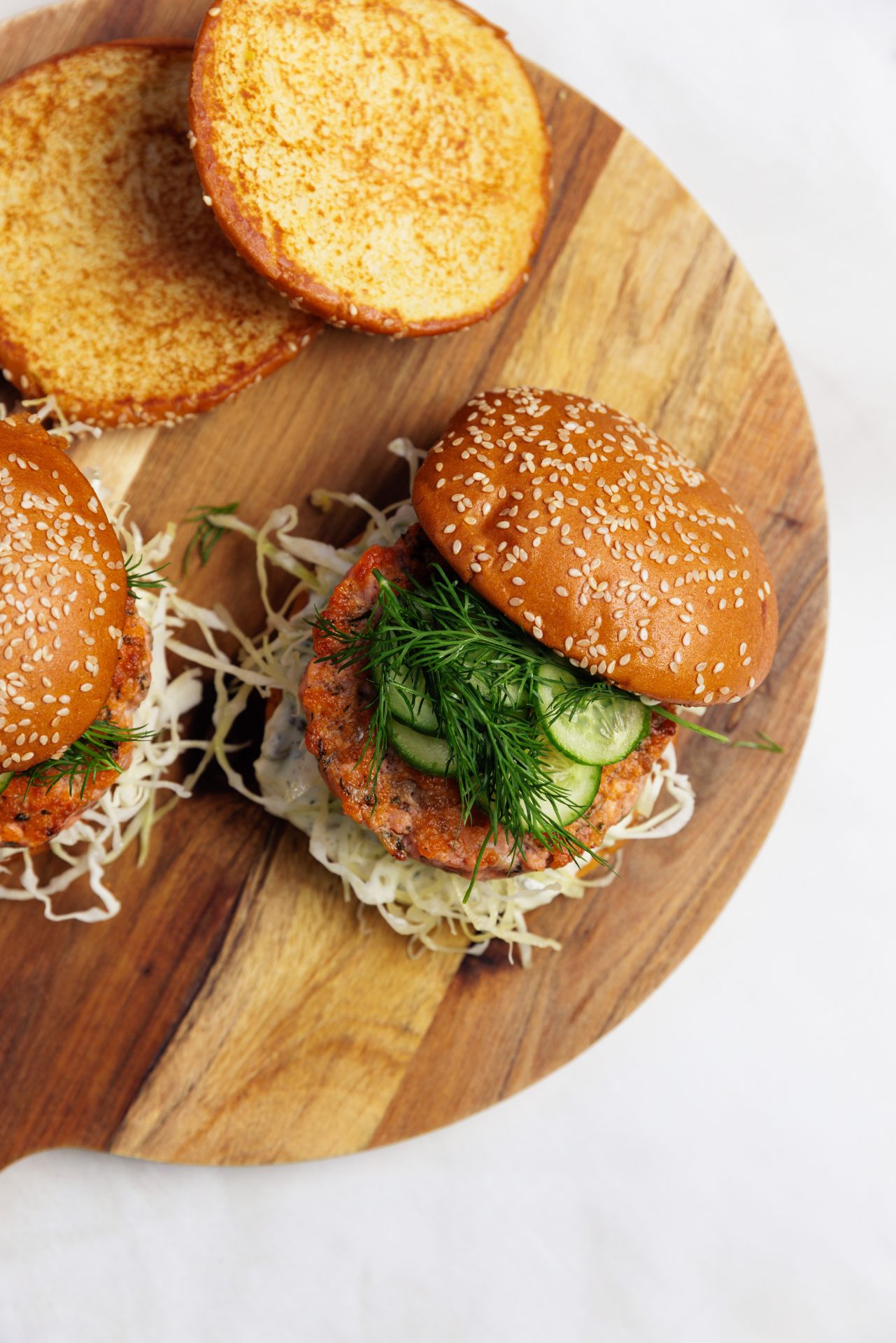 salmon burger recipe buns and salmon burger patties on a wooden serving board